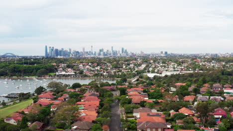 Aerial-drone-flying-backwards-over-residential-houses-with-the-city-skyline-in-the-horizon-in-Sydney-inner-west-Australia