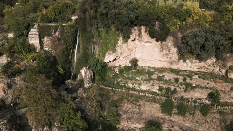 Narrow-waterfall-and-rocky-cliffs-in-Spain,-aerial-drone-view