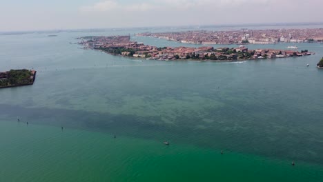 Pull-back-drone-footage-revealing-Venice-islands-at-daytime,-the-popular-romantic-travel-destination-highlighting-stunning-architecture,-turquoise-lagoons-and-canals