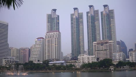 Wolkenkratzeransicht-Von-Hohen-Gebäuden-Vom-Benjakitti-Park-In-Der-Stadt-Bangkok,-Thailand-Handheld-Dynamik