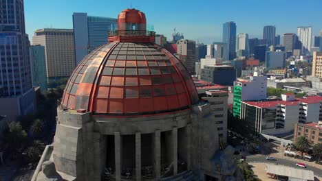 Disparo-De-Drone-De-La-Revolución-Monumento-Edificios-Altos-Atrás-Ciudad-De-México-Paisaje-Urbano-Luz-Del-Día-Cielo-Azul-Clima-Cálido