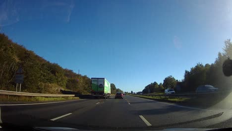 POV-driving-A55-motorway-through-rural-Anglesey-countryside-traffic-on-journey-home-at-day-break