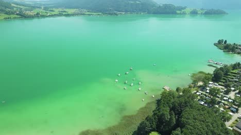 The-drone-reveals-the-serene-Mondsee-lake,-cradled-by-majestic-mountains