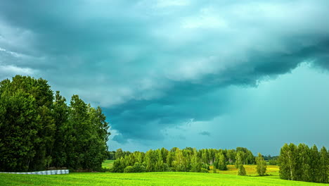 Timelapse-shot-of-cloud-movement-over-green-grasslands-surrounded-by-trees-along-rural-countryside-on-a-cloudy-day
