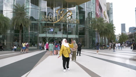 Shoppers-walking-and-taking-photos-in-front-of-the-famous-Siam-Paragon-Mall-in-Bangkok,-Thailand