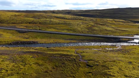 Aerial-orbiting-shot-of-a-vehicle-driving-through-the-Icelandic-countryside