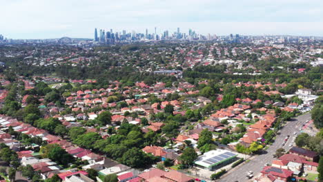Aerial-drone-shot-flying-backwards-over-the-inner-west-suburb-of-Haberfield-with-the-city-skyline-in-the-distance-in-Sydney-Australia