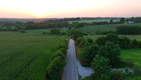Country-road-surrounded-by-rural-farmland-at-sunset