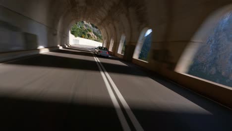 Antena-FPV-Siguiendo-Un-Coche-A-Través-De-Un-Túnel-En-Un-Recorrido-Panorámico-Por-La-Montaña-A-Lo-Largo-De-La-Costa-Mediterránea-De-Mallorca