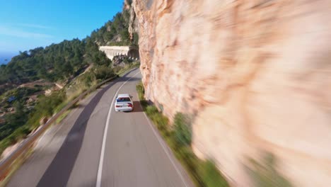 FPV-drone-flying-fast-through-tunnels-following-a-BMW-down-a-scenic-coastal-mountain-highway-in-Mallorca