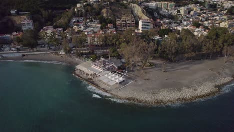 Drone-shot-of-a-café-on-the-beach-beside-a-city