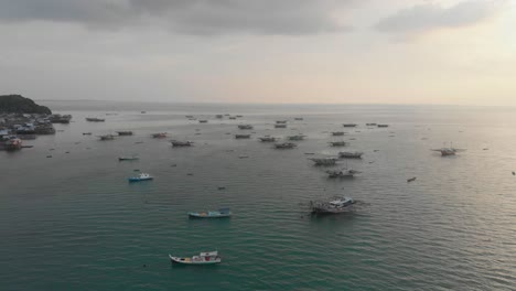 Wide-view-of-boats-docked-near-tanjung-binga-village-during-sunset,-aerial