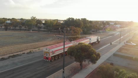 Big-Roadtrain-passing-by-on-street-at-Carnamah-Australia,-aerial