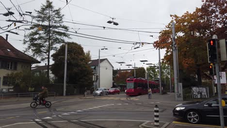 Eine-Rote-Straßenbahn-Fährt-Im-Herbst-Durch-Die-Straßen-Von-Bern,-Schweiz,-Autos-Und-Fahrräder
