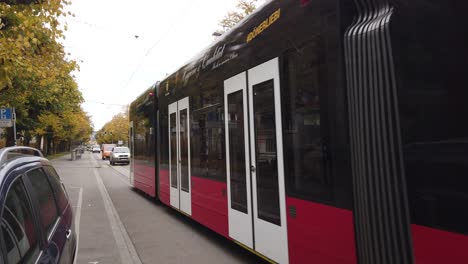 Eine-Straßenbahn-Fährt-Im-Freien-Durch-Die-Straßen-Von-Bern,-Schweiz,-In-Herbstlicher-Schweizer-Landschaft,-Roter-Wagen