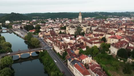 Forward-drone-travelling-along-the-Isle-river,-the-city-of-Périgueux-with-the-Roman-Catholic-Saint-Front-cathedral,-traffic-around-the-bridge