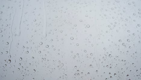 A-slow-motion-footage-of-a-close-view-of-heavy-rain-drops-is-seen-through-a-window-glass