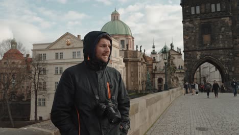 Tourist-on-Charles-Bridge,-Prague-with-historic-buildings-backdrop