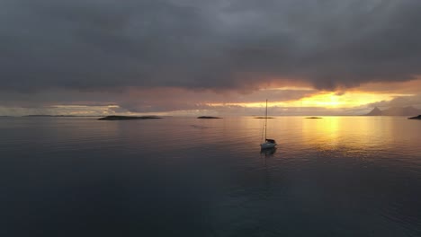 Drone-footage-of-sailing-boat-at-sunset-on-Langsanden-Beach,-Sandhornøy,-Bodø,-Norway