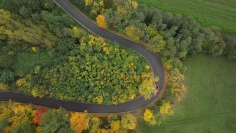 Motor-vehicle-travelling-along-long-winding-countryside-road,-aerial
