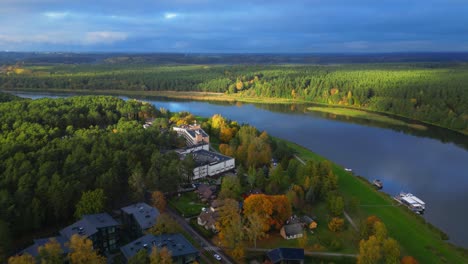 Drone-forward-revealing-Egles-sanatorium-next-to-river-in-Lithuanian-panoramic-landscape