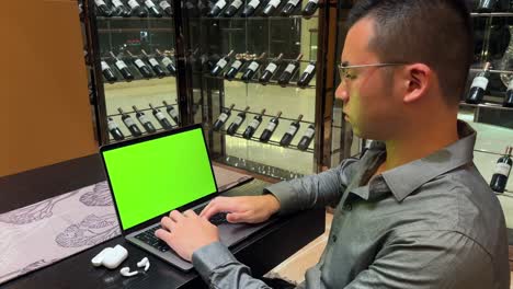 Reicher-Asiatischer-Tausendjähriger-Unternehmer,-Der-Auf-Einem-Laptop-Mit-Grünem-Bildschirm-In-Einem-Luxuriösen-Haus-Tippt
