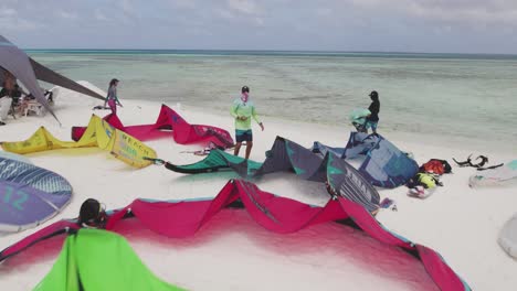 Low-fly-ahead-on-white-sand-cay-with-multiple-kites-and-young-people-enjoy-beach
