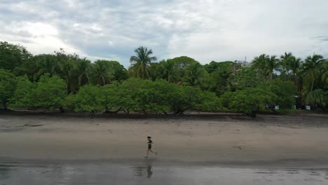 Mujer-Sola-Corre-A-Lo-Largo-Del-Borde-Del-Agua-En-La-Playa-En-Guanacaste-Costa-Rica,-Aérea