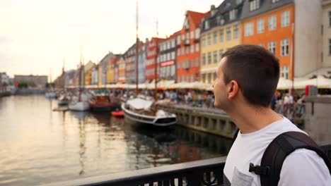 Happy-man-smiles-at-camera-with-busy-Nyhavn-canal-in-background,-Copenhagen