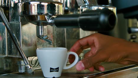 Male-hands-placing-coffee-cup-under-machine-and-waits-for-it-to-pour