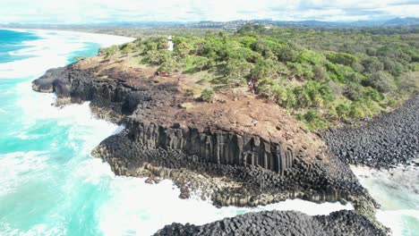 Man-Waves-At-Drone-Camera-Flying-Away-From-Fingal-Headland-In-New-South-Wales,-Australia