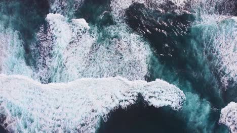 Beautiful-cinematic-top-down-aerial-of-deap-clear-blue-ocean-sea-waves-rolling-to-the-shore