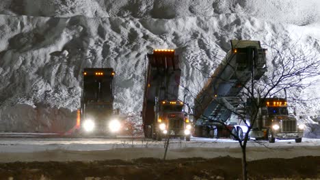 Volquetes-Descargando-Nieve-En-La-Base-De-Un-Enorme-Montón-De-Nieve