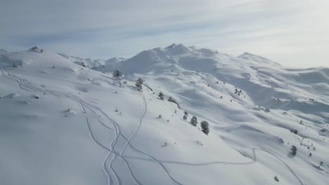 Paisaje-Aéreo-épico-De-La-Cordillera-De-Los-Glaciares-Cubiertos-De-Nieve,-Volando-Sobre-Cumbres-Alpinas-Con-Pistas-De-Esquí-En-Un-Día-Soleado