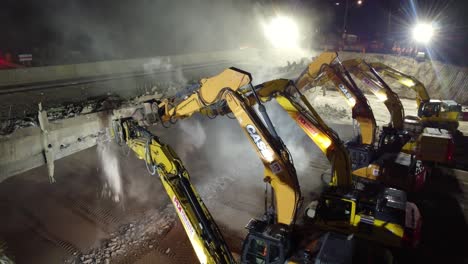 Excavadoras-Trabajando-Demoliendo-Un-Puente-De-Carretera-Por-La-Noche-En-Barrie,-Canadá