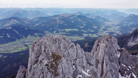 Aerial-of-steep-rocky-alpine-mountain-top-peaks,-epic-landscape-drone-scenery-view-into-valley-and-more-ranges,-Austria