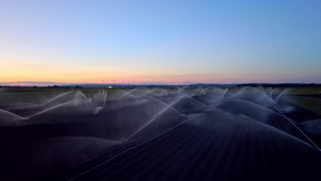 Water-Irrigation-System-In-Farming-Field-At-Dusk---aerial-drone-shot