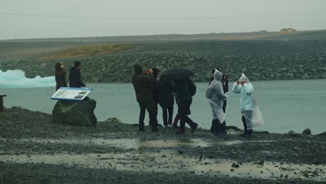 Touristen-In-Regenponchos-Stehen-Am-See-Jökulsarlon-In-Island