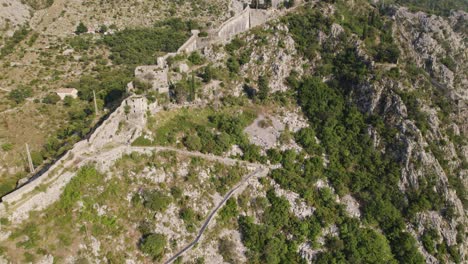 Aerial-view-of-ancient-Kotor-fortress-walls-on-mountainside,-Montenegro