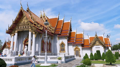 Buddhist-worshipers-going-in-and-out-of-a-community-temple-in-a-local-village-in-Bangkok,-Thailand