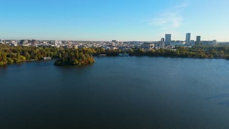 Drone-View-Over-Lake-Herastrau-In-Autumn-With-City-Skyline-In-The-Background,-Bucharest,-Romania