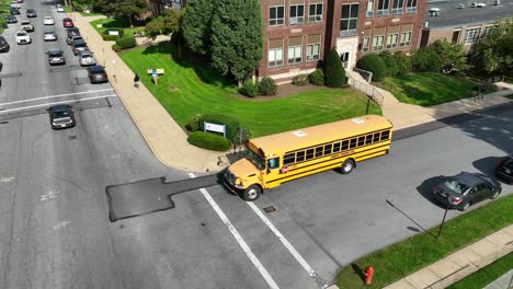 Autobús-Escolar-Conduciendo-Junto-A-La-Escuela-Americana-De-Ladrillo
