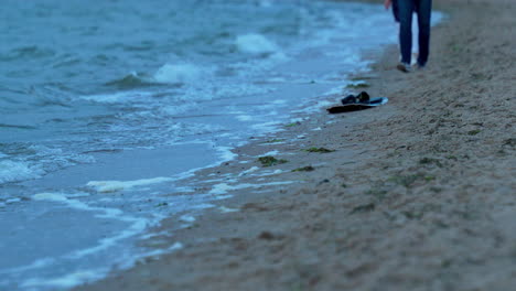 Ruhige-Szene-Von-Menschen,-Die-Am-Strand-Entlanggehen,-Während-Die-Wellen-Das-Ufer-Erreichen,-Zeitlupe