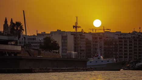 Timelapse-of-sunrise-behind-boats-and-buildings-in-the-city-of-Malta,-Europe