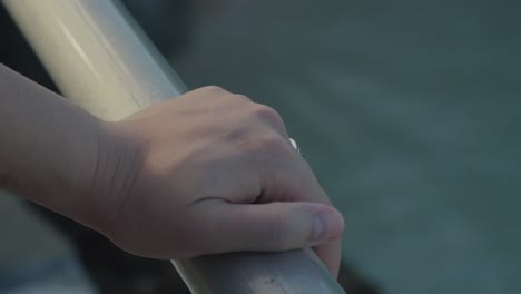 Close-up-shot-of-a-hand-holding-the-railing-at-the-beach