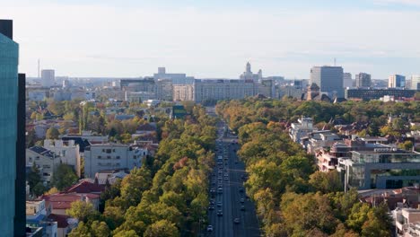 Revelación-Aérea-Lenta-Con-Un-Edificio-Comercial-En-Primer-Plano-Y-La-Plaza-Victoriei-Al-Fondo,-Tráfico-De-Automóviles,-Bucarest,-Rumania