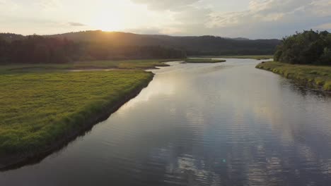 Filmischer-Blick-Von-Einer-Drohne,-Die-Bei-Sonnenuntergang-Auf-Dem-Land-über-Einen-Fluss-Fliegt