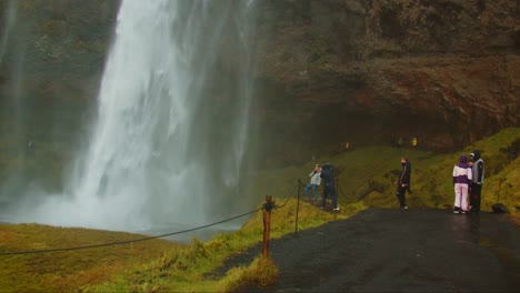 Group-of-tourists-posing-and-taking-pictures-at-Seljalandsfoss-waterfall-in-Iceland
