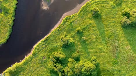 Filmischer-Blick-Von-Einer-Drohne,-Die-über-Einen-Fluss-In-Einer-Wogenden-Landschaft-Fliegt