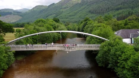 Drone-footage-of-a-group-standing-on-a-bridge-over-the-river-at-the-start-of-Ben-Nevis-as-part-of-the-UK-3-Peaks-Challenge